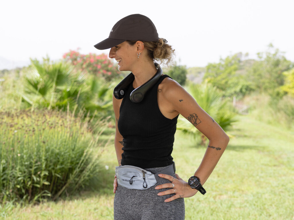 Mujer con gorra deportiva, ventilador de cuello y riñonera deportiva ALE-HOP de ruta en verano.