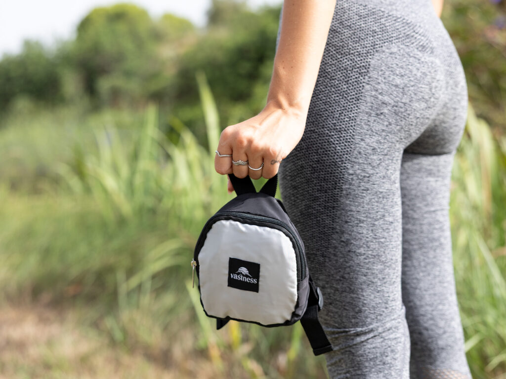 Detalle de mochila plegable compacta gris y negra de ALE-HOP sujeta por una mujer.