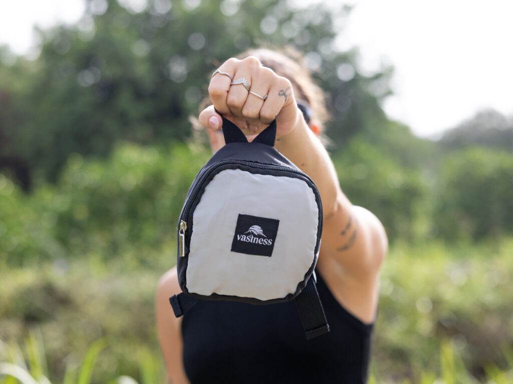 Mujer mostrando una mochila plegable compacta de ALE-HOP ideal para deporte en verano.