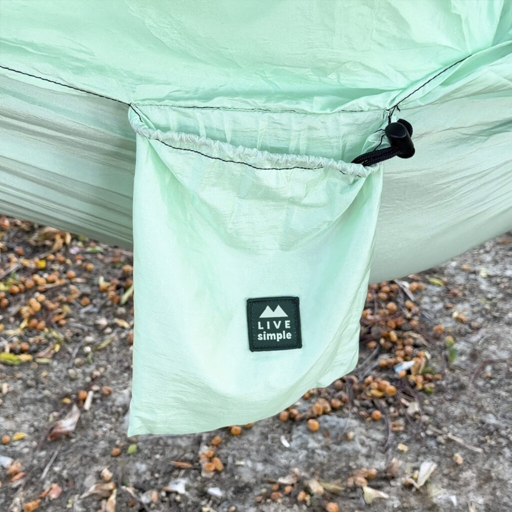 Bolsillo integrado de una hamaca ligera color menta de ALE-HOP colgada de un árbol.