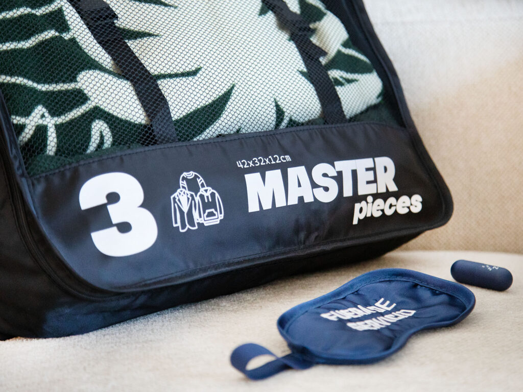 Organizador de maleta para ropa de ALE-HOP junto a un antifaz para dormir azul y tapones.