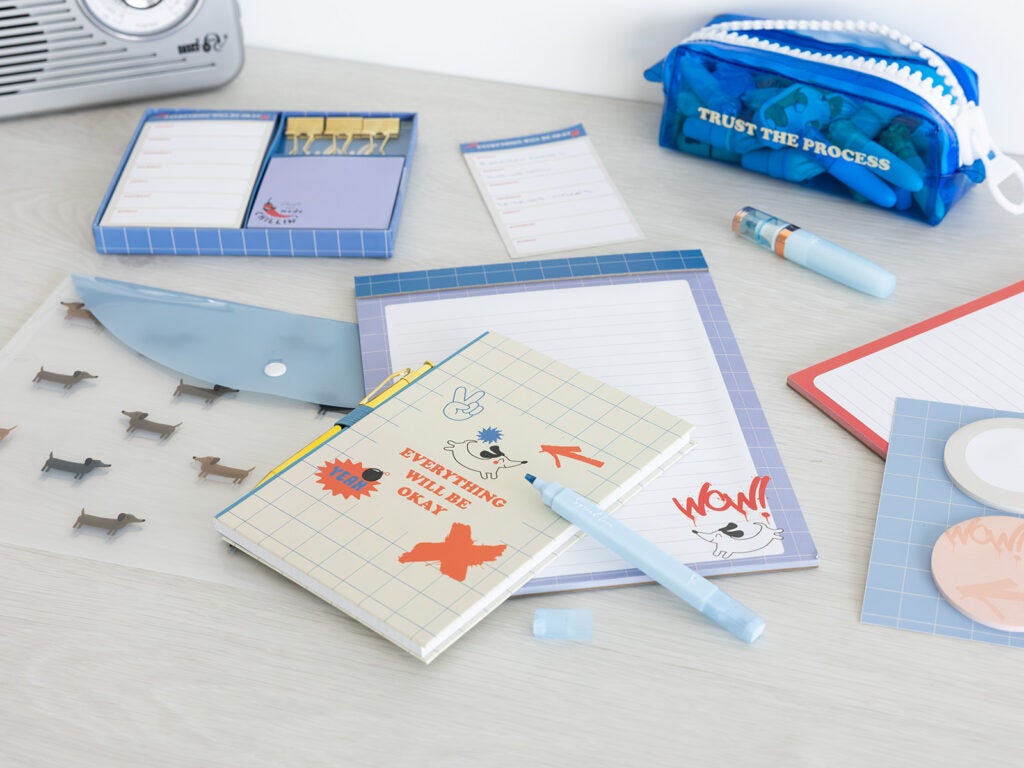 Set de papelería escolar con libreta a5, planificador de escritorio y subrayadores pastel en azul y beige.
