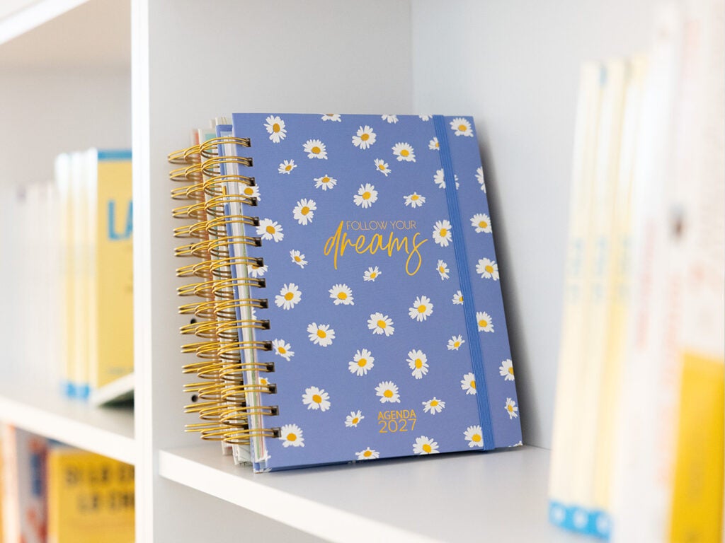 Agenda anual de espiral com margaridas na estante