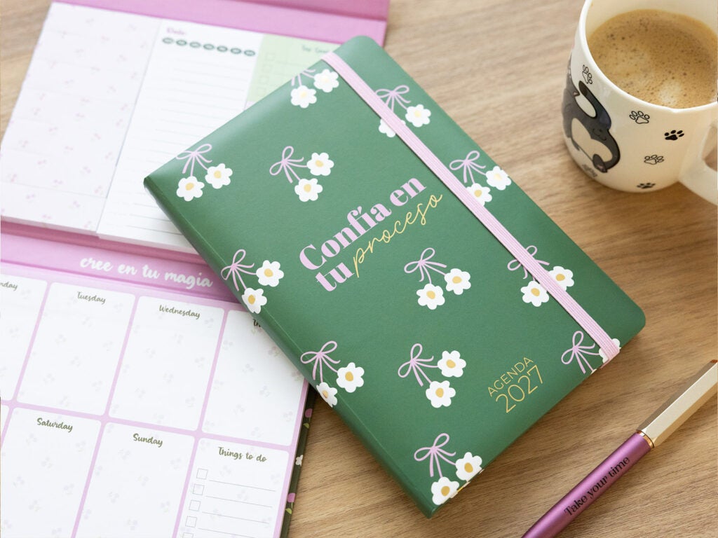 Agenda anual de capa dura verde ao lado de um planeador semanal