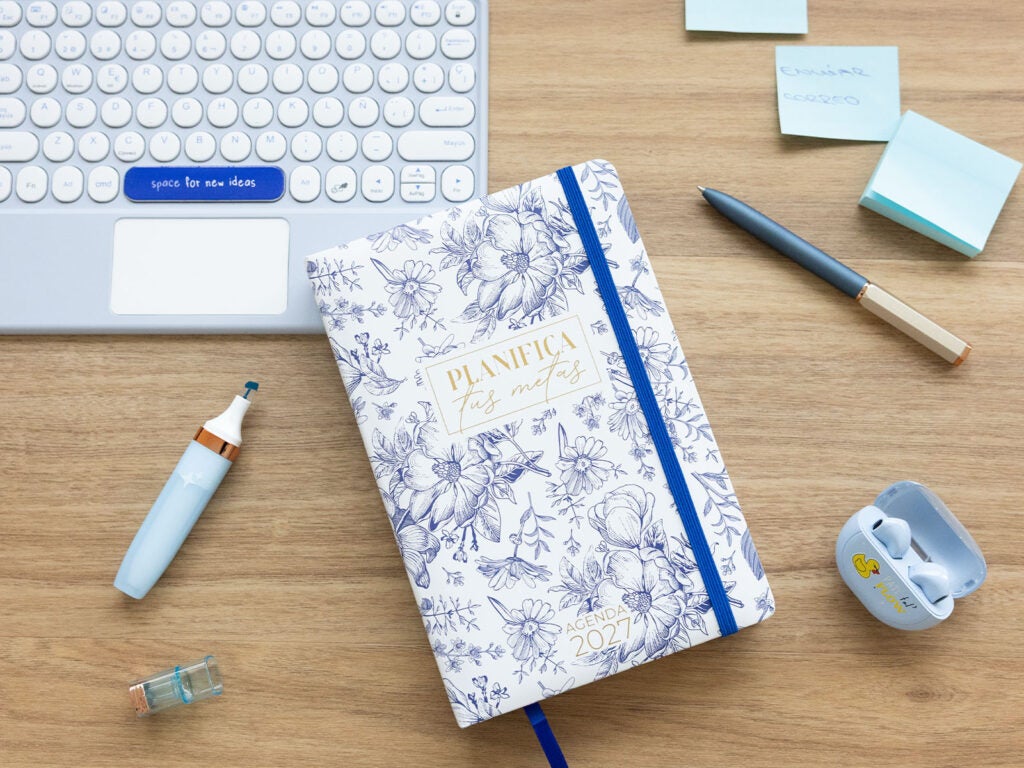 Agenda anual 2027 para o trabalho na secretária ao lado do teclado