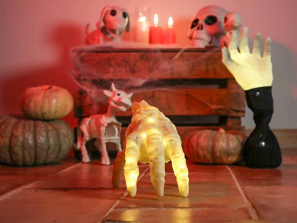 Mano con luz y esqueletos decorativos para fiesta de Halloween